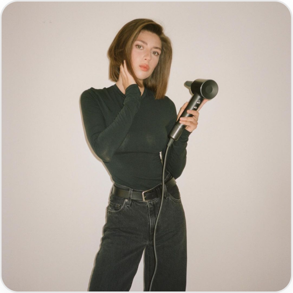 Emma is holding a black Laifen hair dryer with diffuser